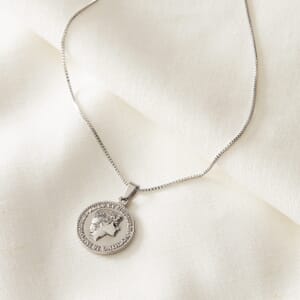 Audrey Hepburn silver stainless steel necklace placed on a cream cloth