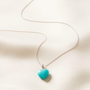 Blue crystal heart pendant necklace placed on a cream cloth