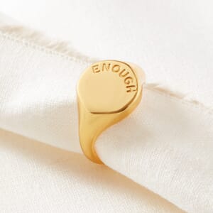 a enough oval signet  18ct gold plated ring wrapped around a cream cloth