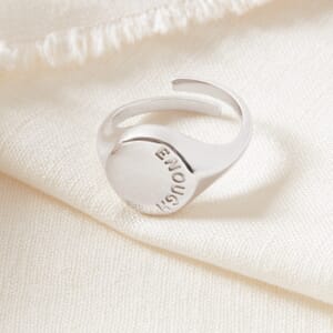 a enough oval signet  sterling silver ring placed on a cream sheet