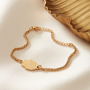 Hamsa Hand Gold stainless steel bracelet placed on top of cream cloth