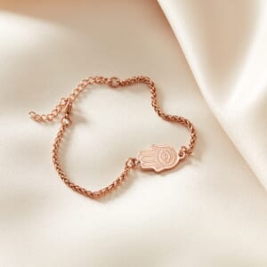 Hamsa Hand Rose Gold stainless steel bracelet placed on top of cream cloth