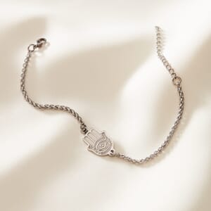 Hamsa Hand silver stainless steel bracelet placed on top of cream cloth
