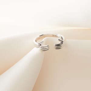 A sterling silver hug ring placed on a cream cloth