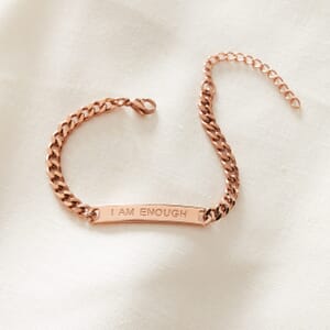 I AM ENOUGH curb stainless steel Rose gold bracelet placed on a cream cloth