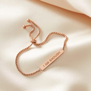 I AM ENOUGH metal stainless steel Rose Gold rope bracelet placed on a cream cloth