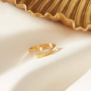 i am strong gold plated stainless steel adjustable ring placed on a cream cloth with gold plate alongside