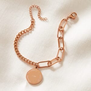 I AM dual rose gold chain stainless steel bracelet resting on a cream cloth