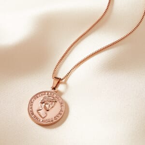 Princess Diana rose gold stainless steel necklace lying on a cream sheet