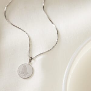 photo of serenity one day at a time silver necklace placed on a cream cloth which is stainless steel 