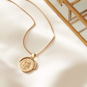 Photo of St Christopher gold necklace placed on a cream cloth