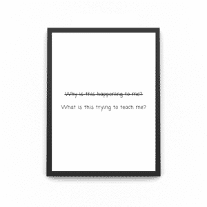 A wooden frame with a quote print saying 'what is this trying to teach me'