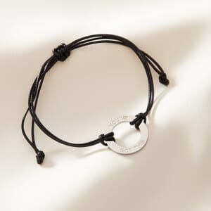 You've got this adjustable wax rope bracelet placed on a cream cloth