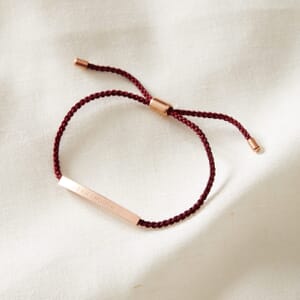 I am enough rose gold stainless steel and rouge rope bracelet placed on a cream cloth