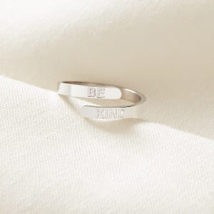 Be kind adjustable stainless steel ring sitting on a cream cloth