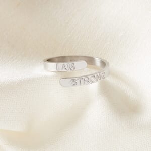 i am strong silver stainless steel adjustable ring placed on a cream cloth